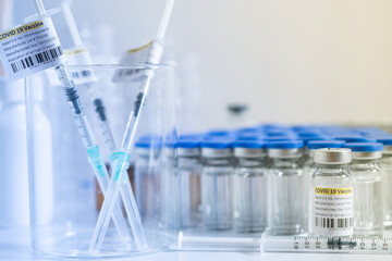 Glass bottle vial and syringe with Covid-19 Coronavirus vaccine in a research medical facility lab. Ampoules with cure on the medical worker laboratory table. Sars-cov-2 pandemic concept.