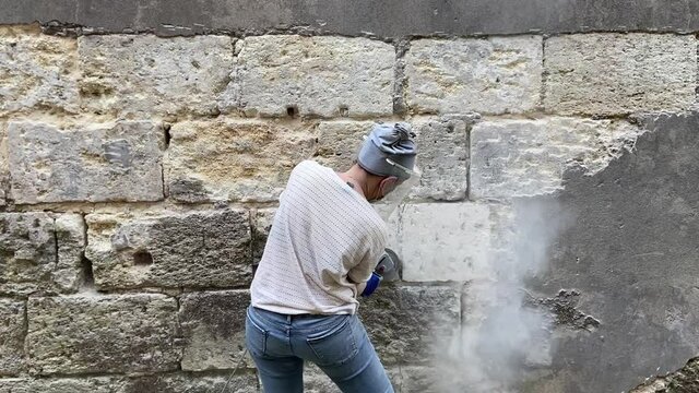 Jeune femme pon&ccedil;ant un mur en pierre bordelaise