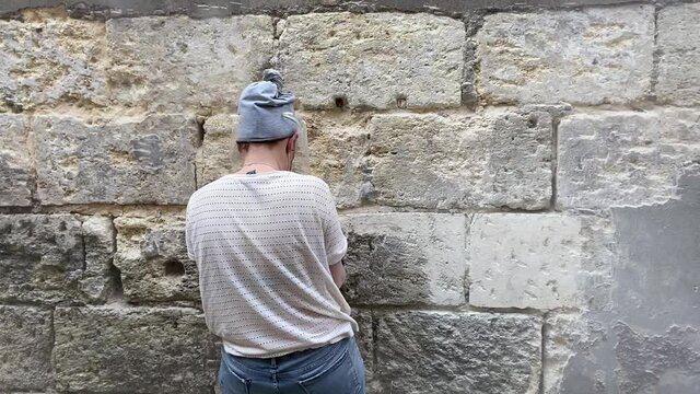 Jeune femme pon&ccedil;ant un mur en pierre bordelaise