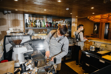 Two masked baristas prepare delicious coffee in the cafe bar. The work of restaurants and cafes during the pandemic.