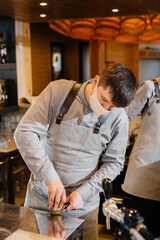 A masked barista prepares delicious coffee at the bar in a cafe. The work of restaurants and cafes during the pandemic.