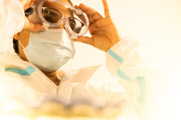 Female doctor or nurse during coronavirus pandemic covid-19. Frontline health care worker in ppe, glasses and mask put on antiviral suit or costume. Health care practitioner in the vaccine laboratory