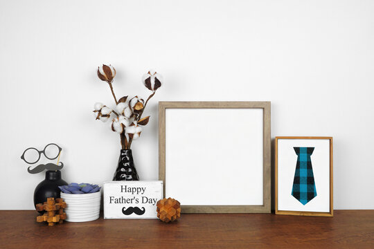 Mock up wood frame with rustic Fathers Day theme decor. Wood shelf against a white wall. Copy space.