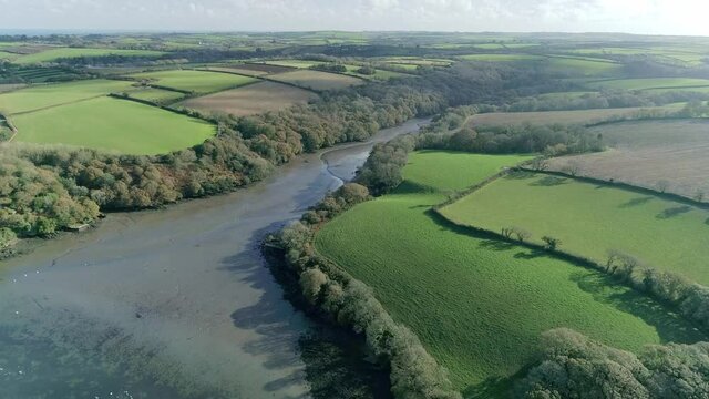 Slow aerial approach over Frenchman's Creek in Cornwall, England, on a sunny afternoon