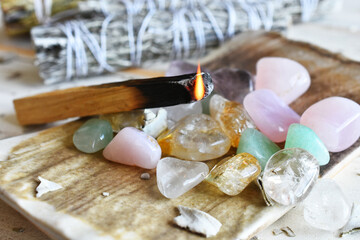 A close up image of burning wooden incense with small polished healing crystals.