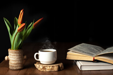 Books on a wooden table. A cup of coffee. Flowers on the book. A stack of books. Workplace. Valentine's day. Love. March 8. Mother's Day