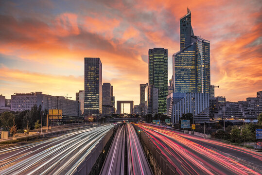 Long exposure sunset on the multinational headquarters and finance institutions in La Defense, Paris business district with car and metro tramway light beams