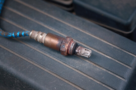 Check and replace gasoline car oxygen sensor. Old and damaged O2 oxygen, lambda sensor, close up of engine spare parts. Part of exhaust system of car with combustion engine.