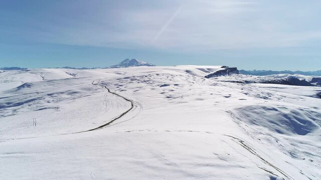 Flying over snowy mountainous terrain on a sunny day