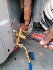 An air conditioning technician opening the valves of the AC unit with a allen key after vacuum the copper line