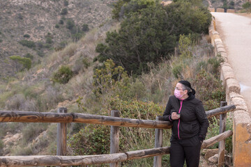 Woman with protective face mask for covid stops for a drink.