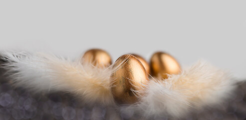 Bronze eggs on feathers. Easter background. Painted eggs.