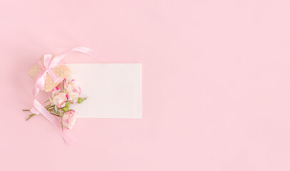 Elegant flowers and greeting card on pink background. Flat lay. Birthday, wedding, spring or summer holidays concept.
