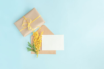 Yellow flowers, gift box and greeting card for spring or summer holidays on blue background with copy space.