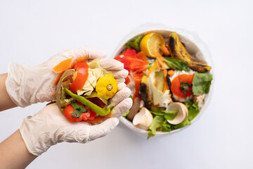 Organic food waste in bowl and in hands on white background top view. Vegetable peelings and food...
