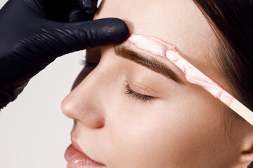 Makeup artist does facial hair removal procedure. Styling and lamination of eyebrows. Woman doing...