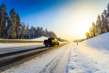 Sunrise on a clear winter morning, pickup rides on the highways in the snow. View from the side of the road. Coniferous forest. Russia, Europe. Beautiful nature.