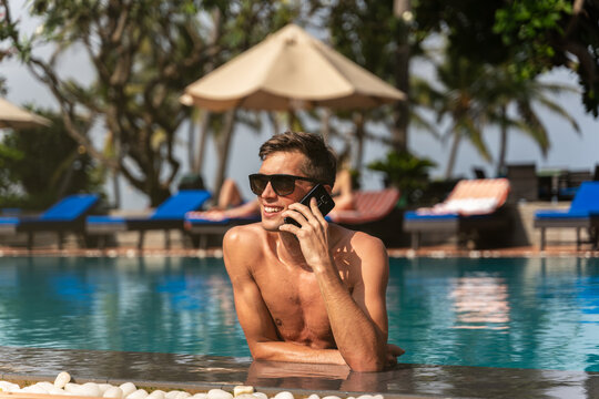 millennial man using the phone on the poolside. picture from the back