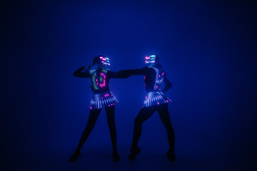 Fototapeta na wymiar Two sexy disco dancers move in UV costumes. Parties and dances.