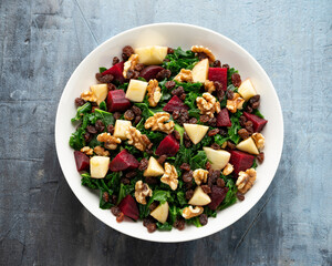 Kale salad with apple, beetroot, walnut and raisins in white plate. Healthy food