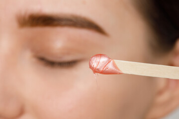 Makeup artist does facial hair removal procedure. Styling and lamination of eyebrows. Woman doing...