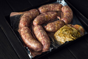 Raw meat sausage and ham on a Sheet pan is prepared for baking in the oven. The national meat dish is prepared before the holidays. Top view