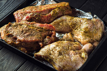 Raw meat veal and chicken legs on a baking sheet are prepared for baking in the oven. The national meat dish is prepared on the eve of the holidays
