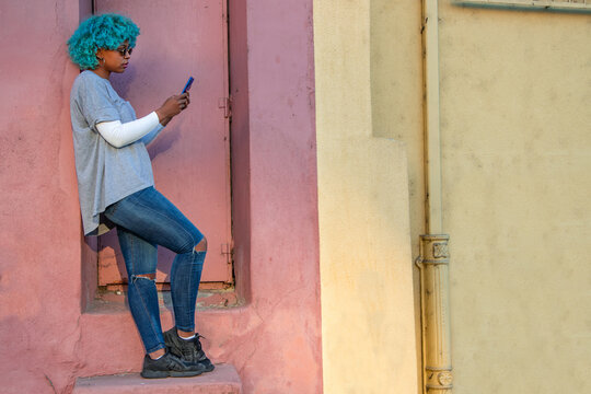 afro american girl with colored hair and mobile phone on the street