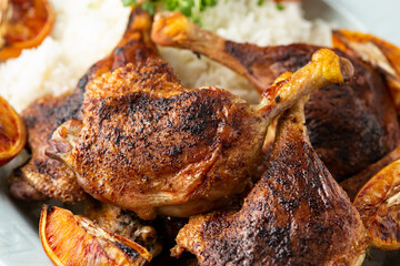 Slow cooked aromatic duck legs with basmati rice and side salad served with orange wedges.