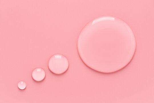 Water drops in speech bubble shape on pink background. Transparent liquid speech balloon. Place for text.
