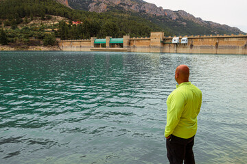 Hairless man observing the Guadalest swamp, on a cloudy day.