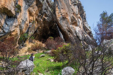 Fototapeta na wymiar Hiker taking photos of a cave in a mountain.