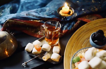Plate with mix nuts and sweets on a eastern styled table with tea in armudu