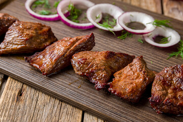 fried Kebab of veal , skewers of vial with onion and greens on old wooden table close up