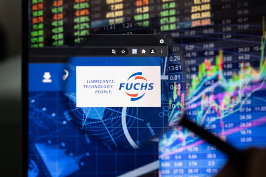 Fuchs company logo on a website with blurry stock market developments in the background, seen on a computer screen through a magnifying glass