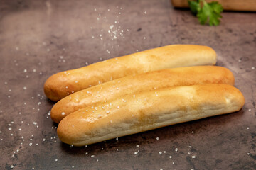 Breadsticks with sea salt being sprinkled on top