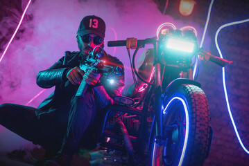 Naklejka na ściany i meble A special force agent with a rifle is hiding behind a futuristic motorbike and shooting. Cyberpunk concept.