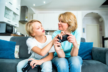 Child son and mother playing video games together at home - Happy family having fun on weekend daytime - Family and videogame concept