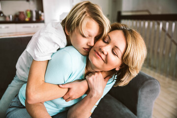 Fototapeta premium Happy mother and son hugging each other at home - Family concept