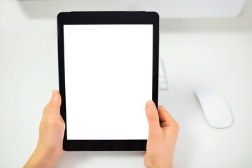 Obraz na płótnie Canvas Mockup image of a woman holding black tablet pc with blank white screen. Top view women showing blank screen tablet in hands over office supplies and White Desk.