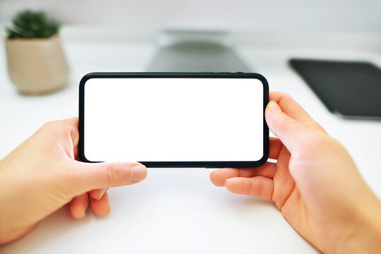 Mockup image of woman's hands holding and using a black mobile phone with blank screen horizontally for watching.