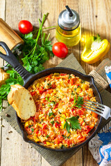 Traditional Turkish dish. Mememen (fried vegetables with scrambled egg) in a cast iron frying pan on a wooden table.