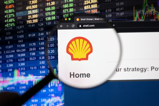 Royal Dutch Shell company logo on a website with blurry stock market developments in the background, seen on a computer screen through a magnifying glass