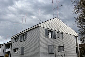 House with metal poles around. They suggest a new shape the house that is going to be rebuilt. Compulsory part of building procedure in Switzerland so that the neighbors can bring objections. 