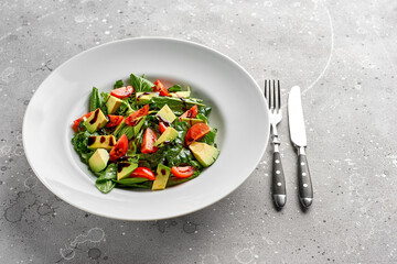 Fototapeta na wymiar Salad with avocado, lettuce, tomato and flax seeds on gray background.Close up