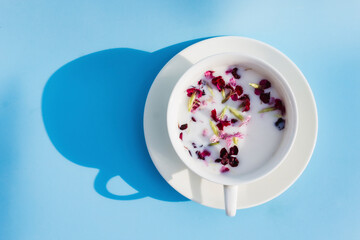 White Cup with vegan milk and flowers on a blue background. Concept of vegetarian drinks and food, herbal teas, beauty and health, Spa