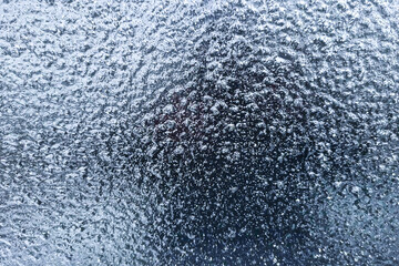 Freezing rain ice on car window glass. Frozen water on the window. Transparent glass with ice is translucent, freezing rain. Car windshield after rain - road safety in