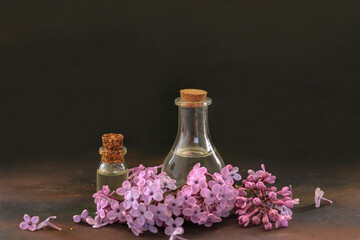 Obraz na płótnie Canvas Lilac flower and lilac oil in bottle on wooden table