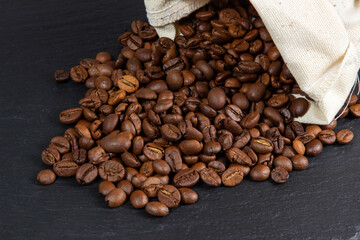Coffee beans scattered from a bag on a black table