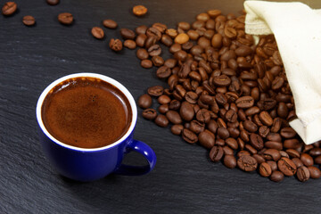 A cup of coffee on the background of scattered grains from the bag